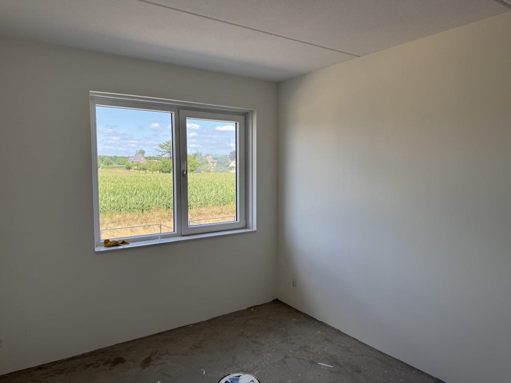 Lege slaapkamer in een nieuwbouwwoning met gladde lichte wanden en een raam